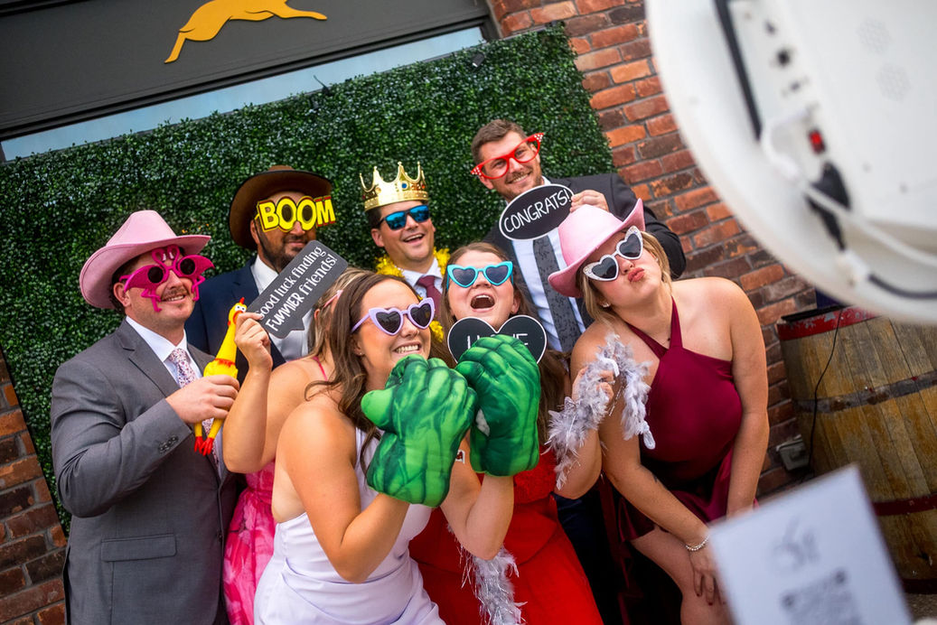 Hochzeitsgäste mit Requisiten vor Fotobox