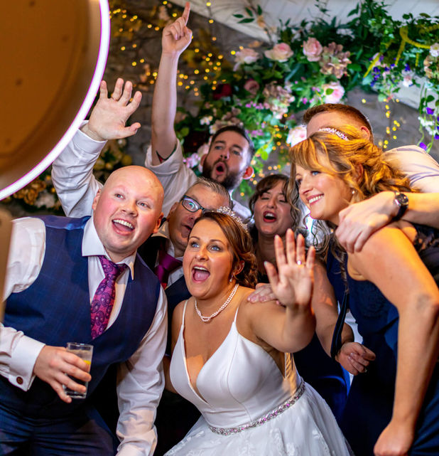 Fotobox für Hochzeiten mit Gästen vor eleganter Hochzeitsrückwand