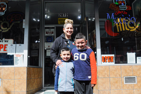 Woman with two smiling boys in front of an open store