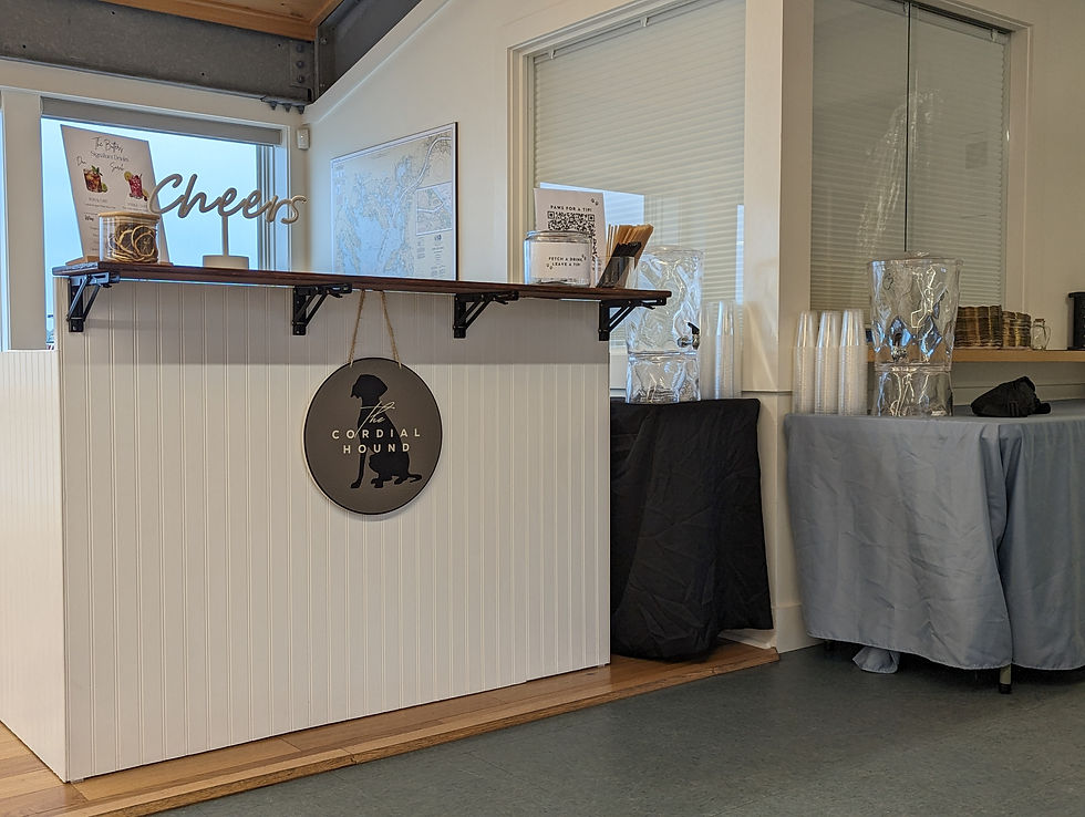 A beautiful white bar with a green sign hanging down that reads "The cordial Hound".