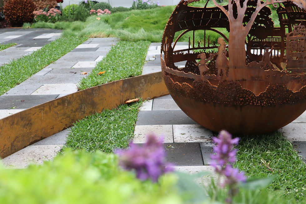 A firepit with a girl playing set within paving and lawn