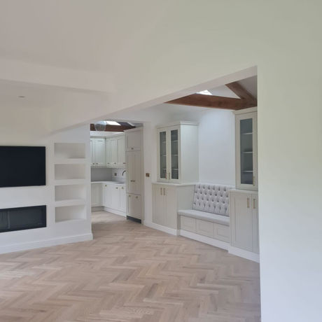 Completed garage conversion featuring exposed timber ceiling beams, herringbone flooring, bespoke fitted furniture and an open-plan kitchen and living area.