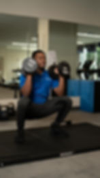 Man squatting holding 40-pound dumbbells on ROGUE mat in gym.