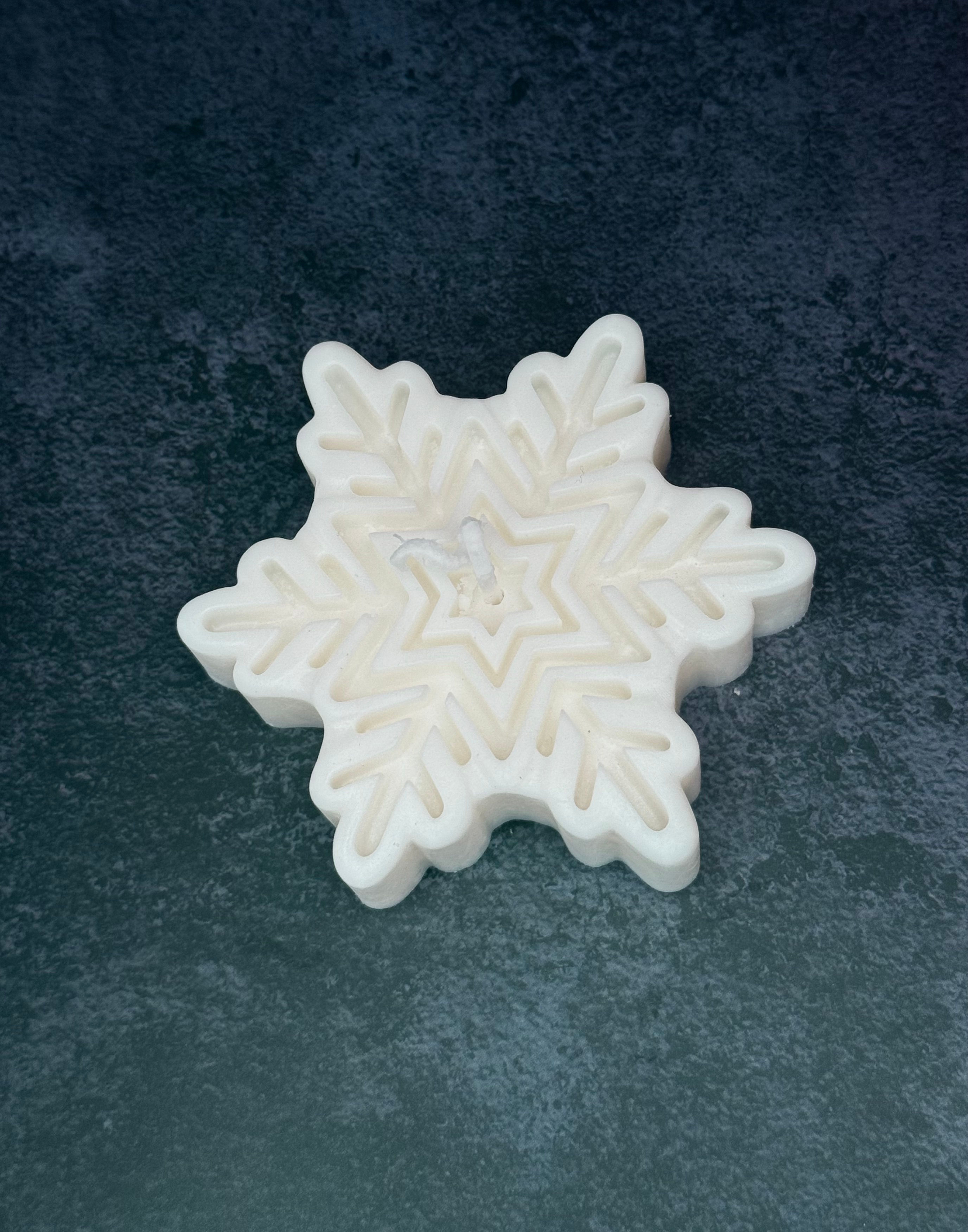 White snowflake-shaped candle on a dark background for decoration.