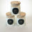 Thumbnail: Three glass candles with wooden lids and labels on a white background.