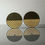 Thumbnail: Two round black and gold earrings with concentric circle design on reflective surface