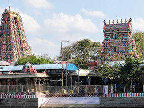 Colorful Hindu temple gopurams rise above a waterfront complex under a blue sky, with a Tour Times logo in the corner. Sowmya Narayana Perumal Temple