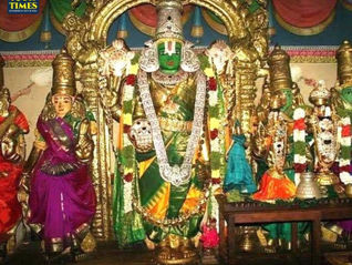Colorful Hindu temple idols, centered on a green-faced deity in a gold arch, with smaller statues and a TOUR TIMES watermark. Thirutholaivillimangalam Temple