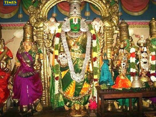 Colorful Hindu temple idols, centered on a green-faced deity in a gold arch, with smaller statues and a TOUR TIMES watermark. Thirutholaivillimangalam Temple