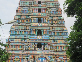 Colorful temple tower with intricate carvings and statues, set between trees. A "Tour Times" sign is in the top right corner. Thirunagai Temple