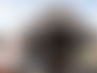 Colorful temple entrance with intricate statues under a blue sky. People enter below. Tamil text on signs. White clouds in the background. Swamimalai Murugan Temple