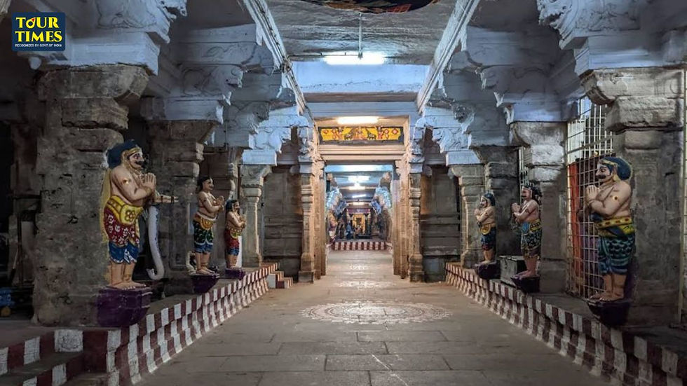 Temple corridor with colorful praying guardian statues, stone pillars and lit ceiling, Tour Times logo at top left. Thirupullani Temple