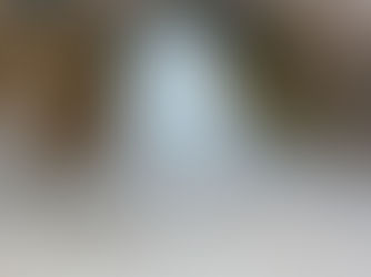 A large ice stalagmite inside a rocky cave. A trident adorned with cloth and bells leans against it. Text: Tour Times at the top left.Amarnath Cave Temple