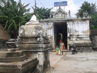 A woman and child walk near an ancient, intricately carved temple entrance. Lush green trees and a bike are visible. Sign reads "Tour Times. Thiru Sempon Sei Temple