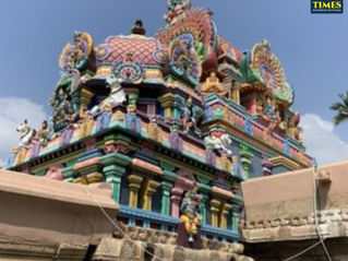 Vibrant Hindu temple tower with intricate sculptures and colorful patterns, set against a blue sky. Tour Times logo in the corner.Sri Purushothaman Perumal Temple