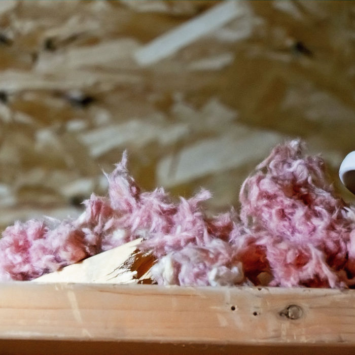 Some insulation and wiring in an attic on top of a rafter beam.