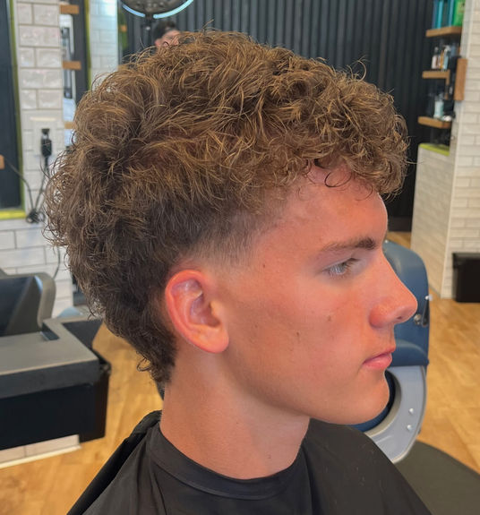 Curly mullet haircut with taper fade and natural curls at R&R Head Labs Denver