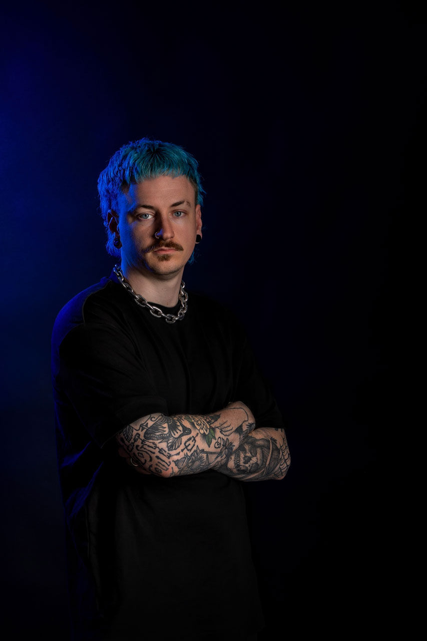 Portrait of young man with coloured hair and tattoos, taken in the Southend studio.