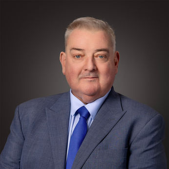 Corporate headshot of a man with a blue tie, in front of a dark grey background.
