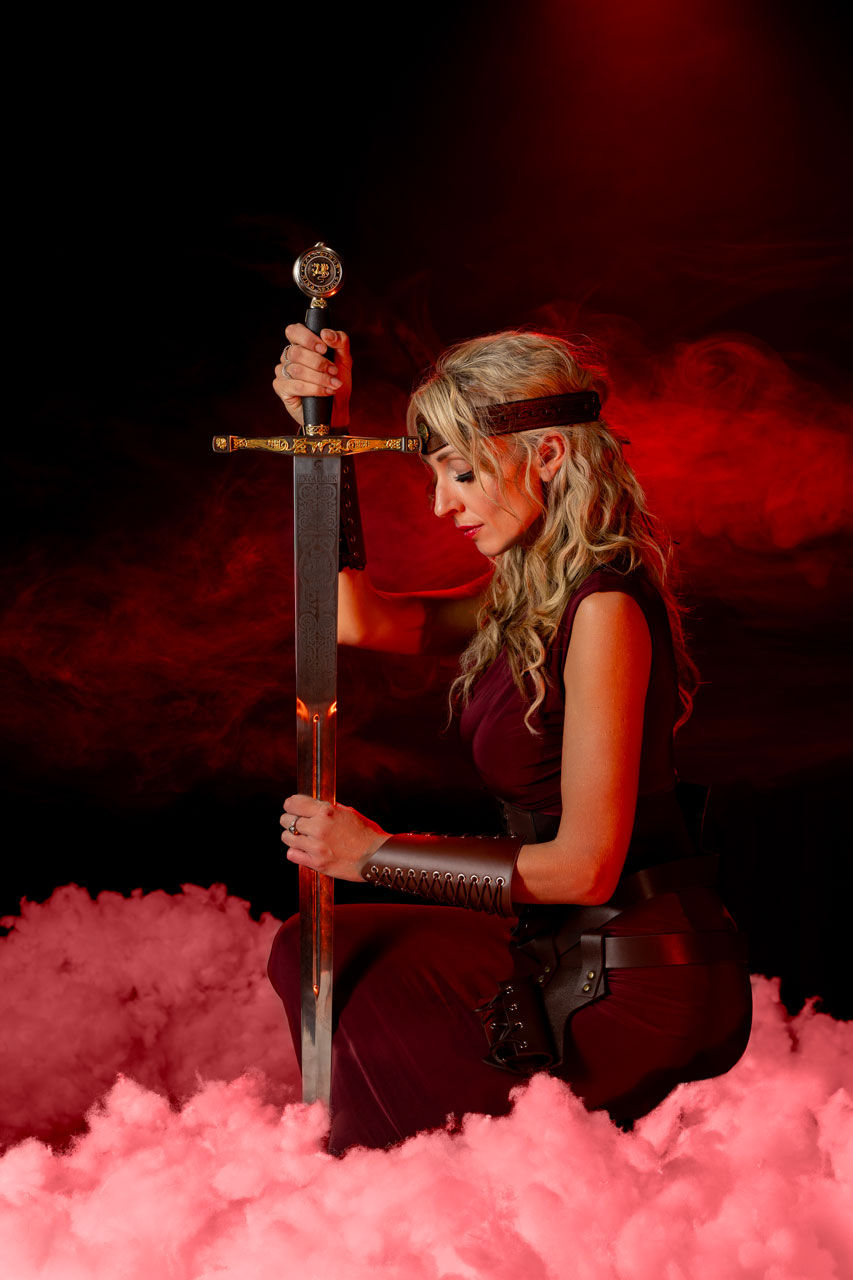 Themed photoshoot of a lady warrior kneeling with a sword, taken in Southend studio.