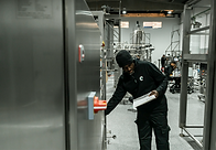 Technician inspecting industrial equipment in a manufacturing facility while holding a che
