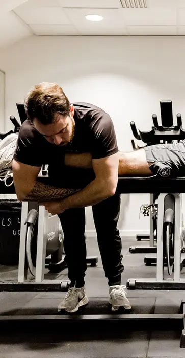 Alexis de Powerforge ajuste manuellement la posture d’un athlète sur banc, illustrant la précision biomécanique et le haut niveau d’exigence derrière chaque programme Powerforge