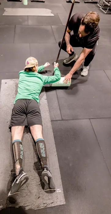 Alexis de Powerforge corrige un athlète au sol avec rouleau de massage, illustrant l’importance du suivi, de la posture et de la prévention dans l’approche Powerforge