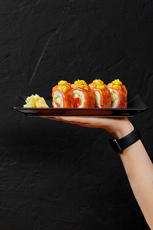 female-hand-holding-plate-with-sushi-rolls-with-seared-salmon-cream-cheese-red-tobiko-mang