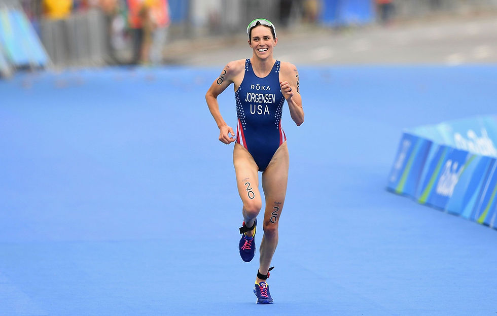 Athlete in blue triathlon suit joyfully runs on a blue track. "Jorgensen USA" visible. Markings "20" on arms and legs.