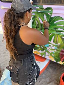 Beth of Just B Paints painting a floral Hawaiian themed mural on a purple bus.
