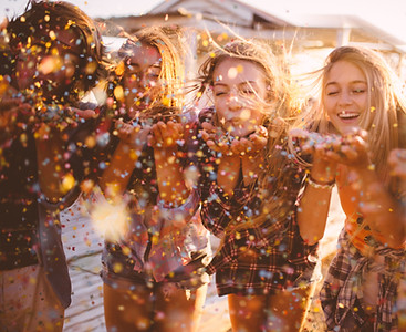 a group of young friends blowing confetti at an event