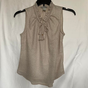 A tan sleeveless blouse with gold accents and a tie at the neckline.