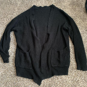 A plain black buttonless cardigan with pockets on either side