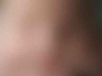 Close do rosto de um bebé. Ele está com os olhos fechados e com o rosto apoiado nas mãos