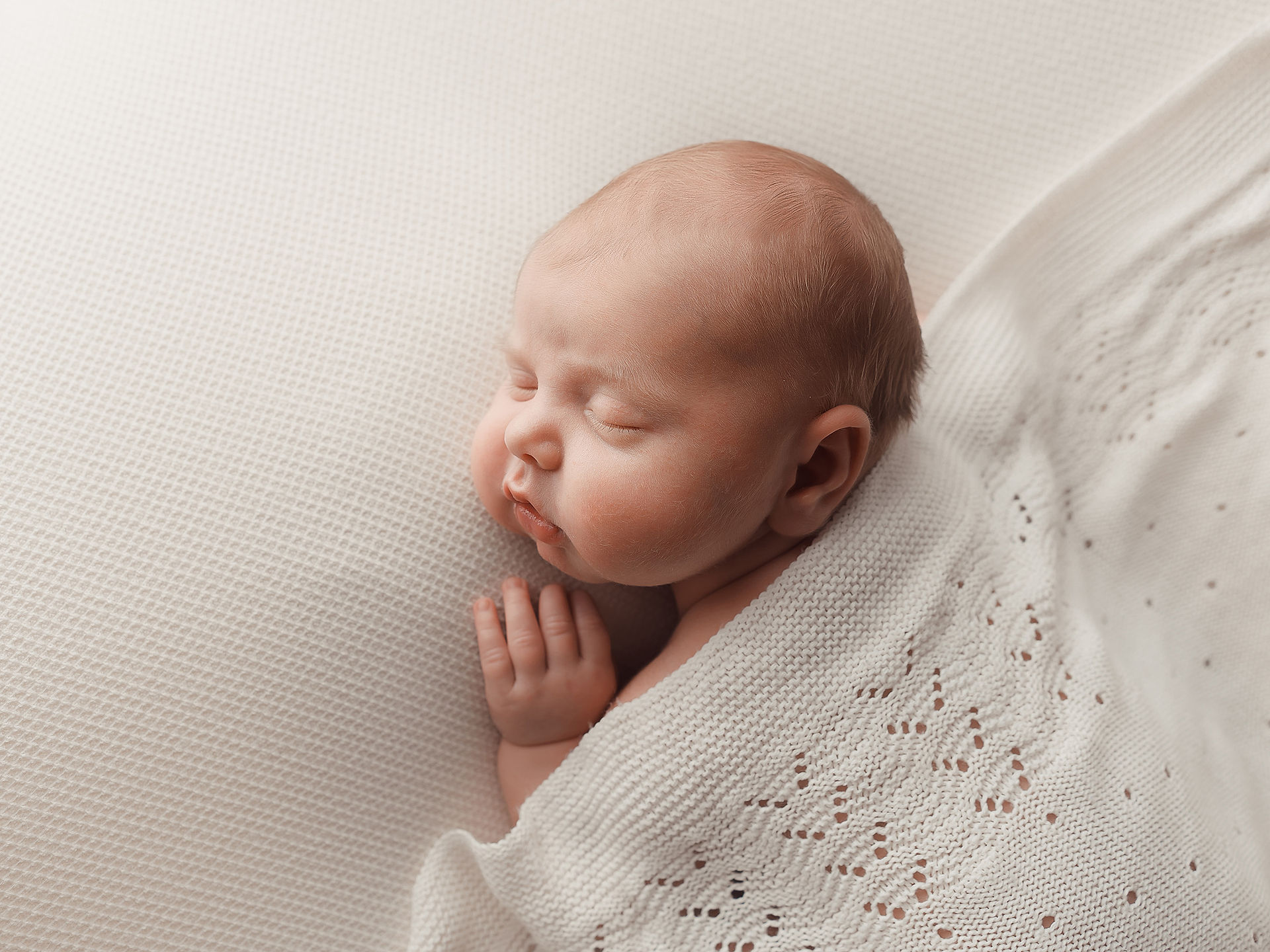 fotografia de bebe em sess~ao fotografica posando deitado em manta branca