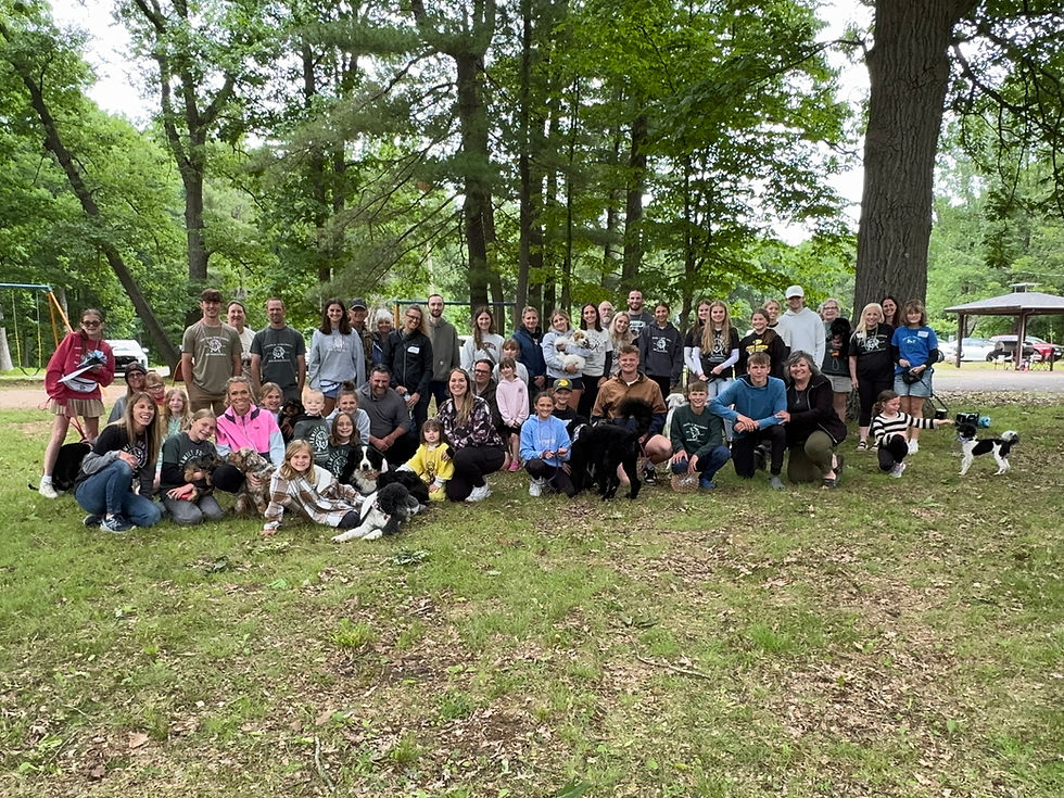 Group photo of CW Bernedoodles families, children, and their dogs gathered outdoors during Family Fun Day, celebrating the growing Bernedoodle community with puppy alumni and lifelong friendships.