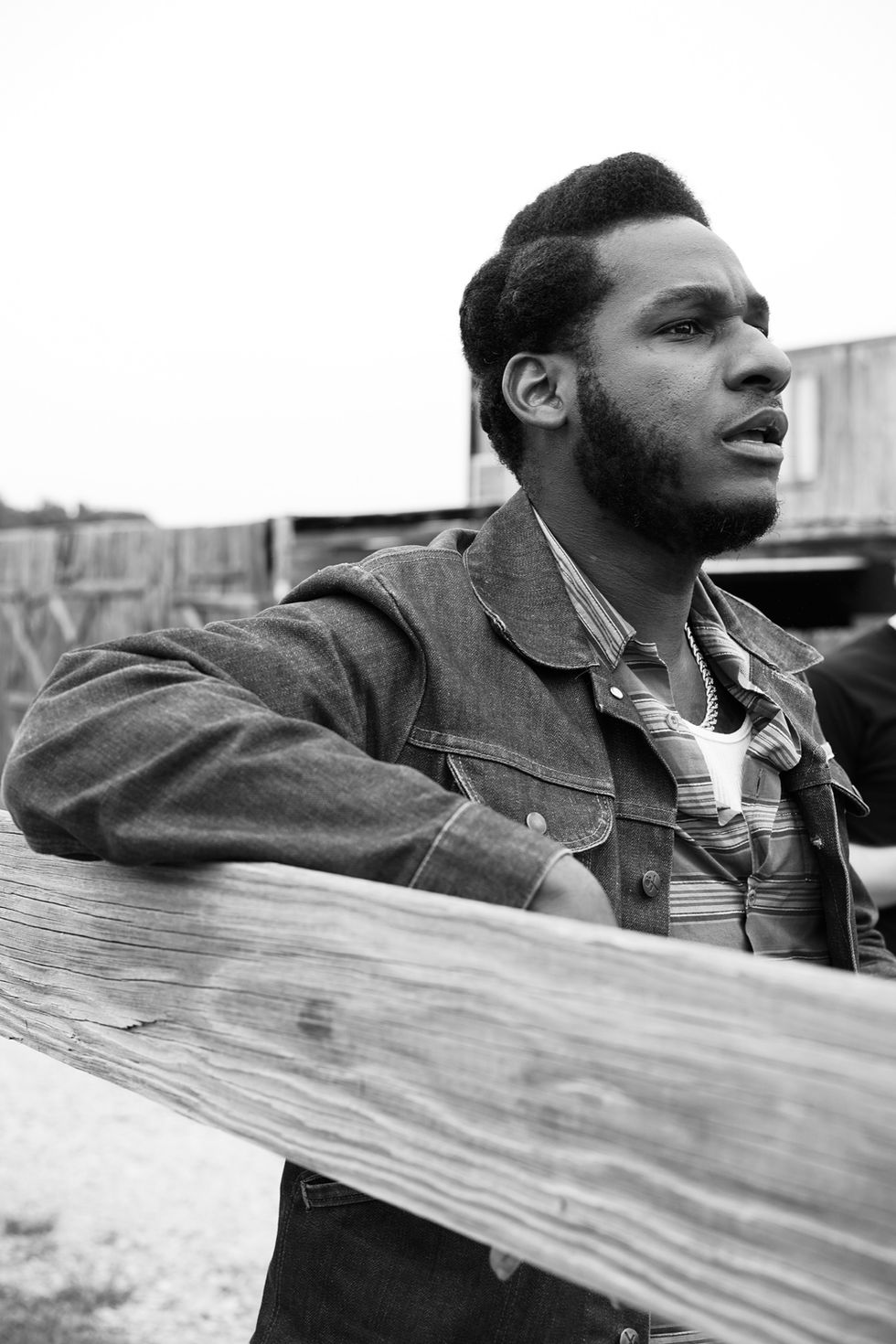 Musician Leon Bridges leaning against a wooden fence during the filming of the Khruangbin b-sides music video featuring Leon Bridges