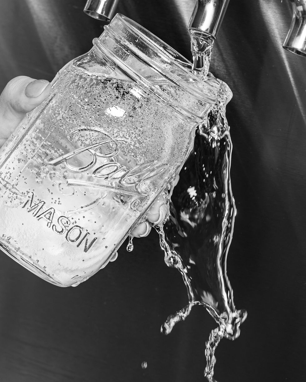 Cider spilling out as its being poured into a mason jar
