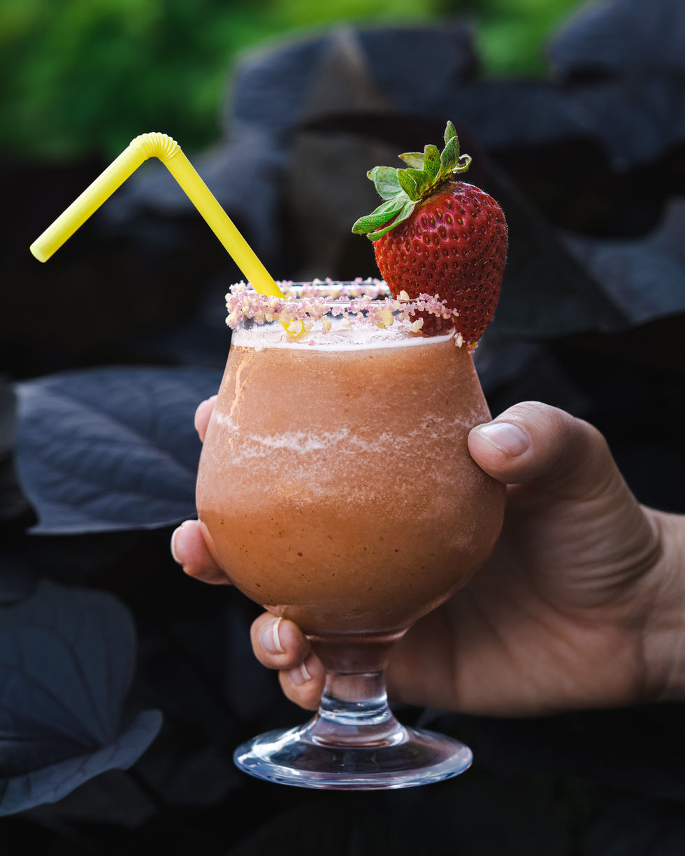 Hand holding a strawberry garnished slushee