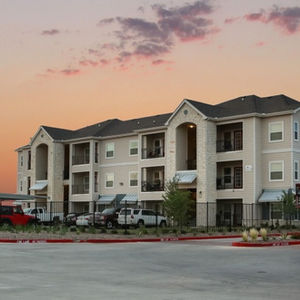 Large apartment building at Residences at Midland with a sunset backdrop, showcasing the garden-style architecture of the complex.