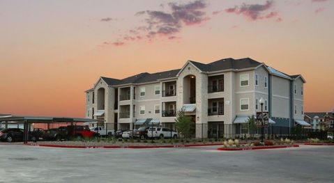 Large apartment building at Residences at Midland with a sunset backdrop, showcasing the garden-style architecture of the complex.
