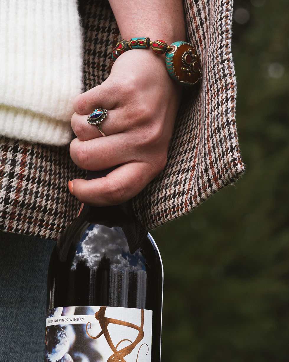 jewelry laden hand grasping a wine bottle