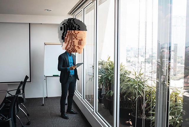 Empresario con una tableta mirando por las ventanas de su oficina hacia la ciudad, Malasia.