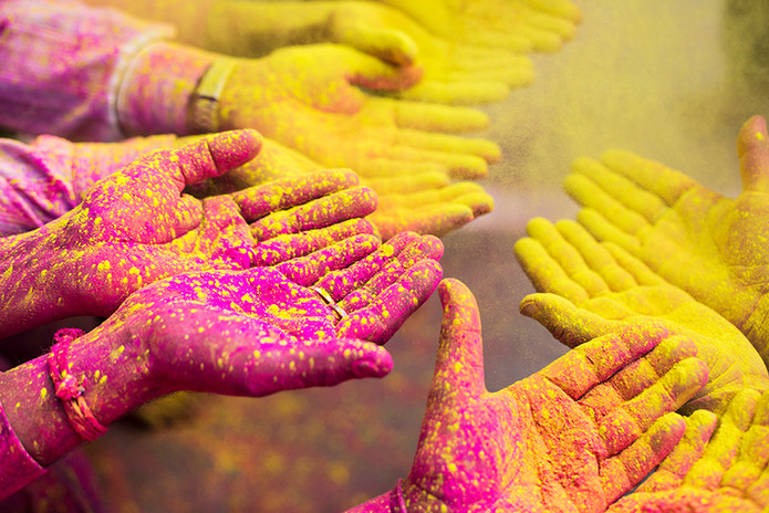 Primer plano de manos cubiertas con polvos de colores del festival Holi, India.