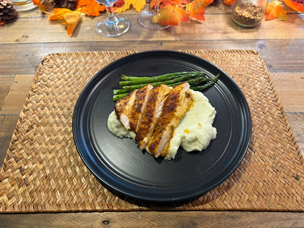 Smoked paprika chicken sliced over cauliflower-potato puree with roasted asparagus on a black plate