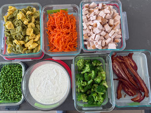 Components for turkey bacon ranch tortellini salad: cheese tortellini, shredded carrots, diced turkey, peas, Greek yogurt ranch, broccoli and crisp bacon in separate glass containers