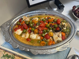 Cherry tomatoes, Castelvetrano olives, capers and garlic in a baking dish before roasting, for roasted cod with tomatoes
