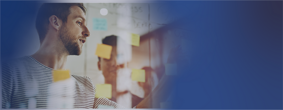 Team member leading a strategic planning session using sticky notes on a glass board in a small business meeting room