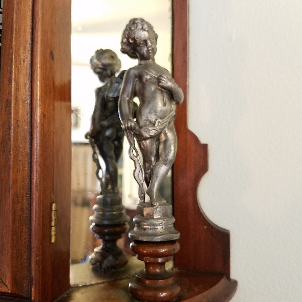 Close of photograph of a metal cherub mounted on the right side of the clock.