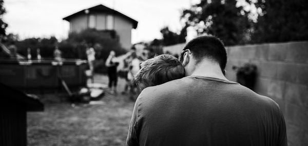 Táta objímá syna na zahradě při rodinném dokumentárním focení.